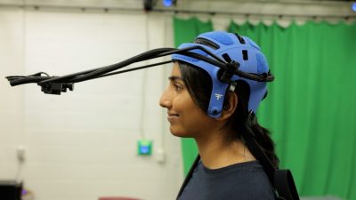 Graduate student Varshita Usem wears a blue helmet with a long harmed camera attached to it.