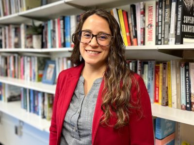 Woman standing in office with bookshelf behind her.